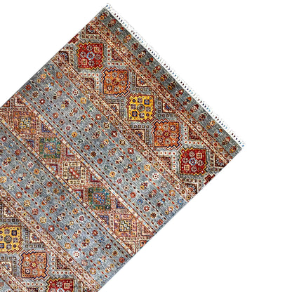 Carpet corner with geometric diamond shapes, a gray background, and a decorative border, with fringes visible