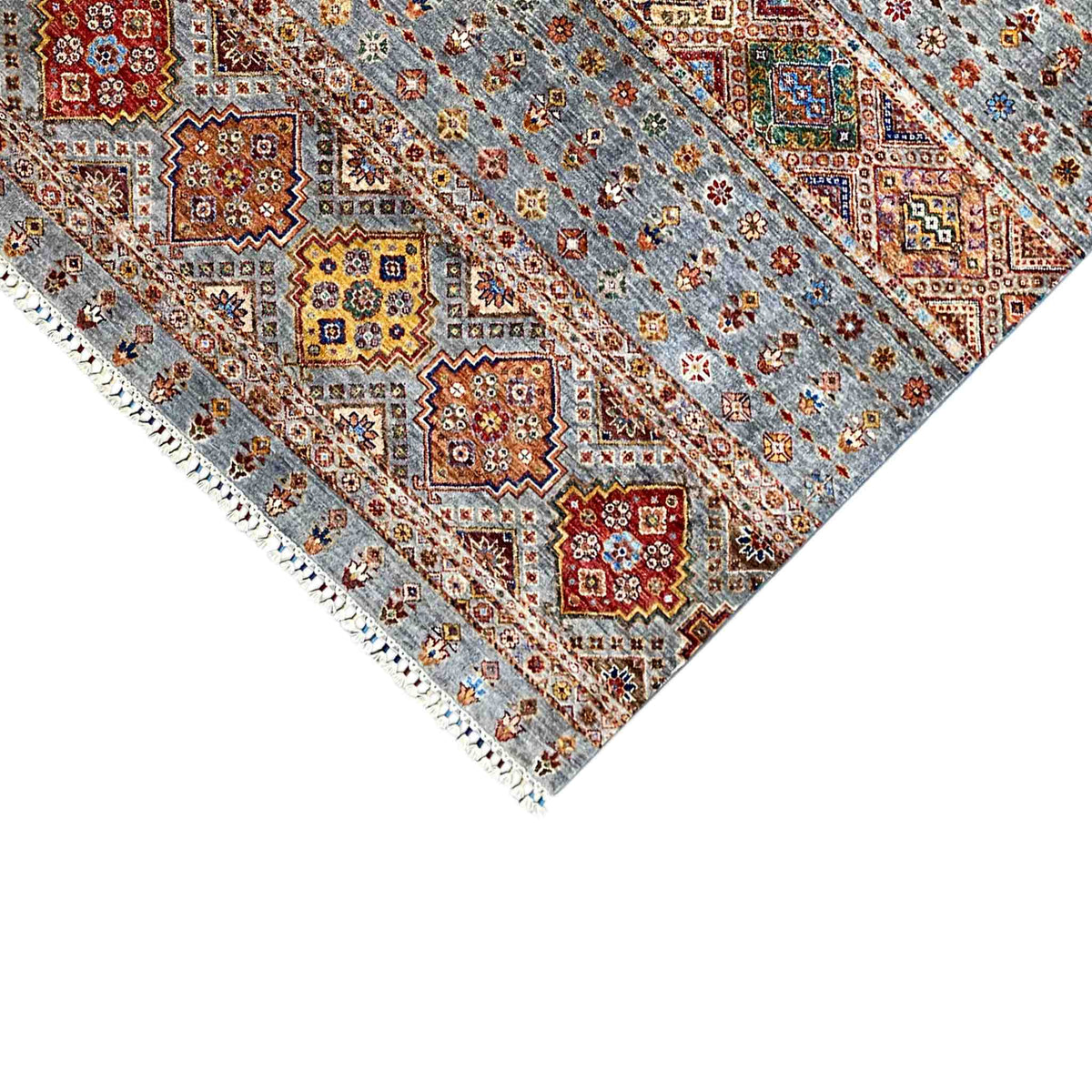 Rug edge with fringe and geometric quadrilaterals in gray, red, and yellow, shown in detail