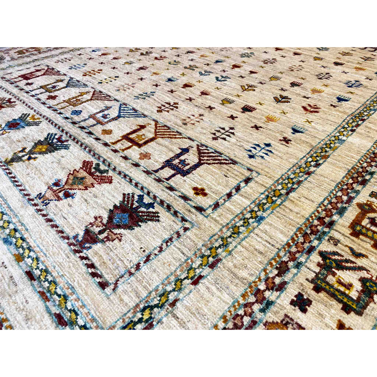 Close-up of a rug with a light background, framed motifs, and decorative bands