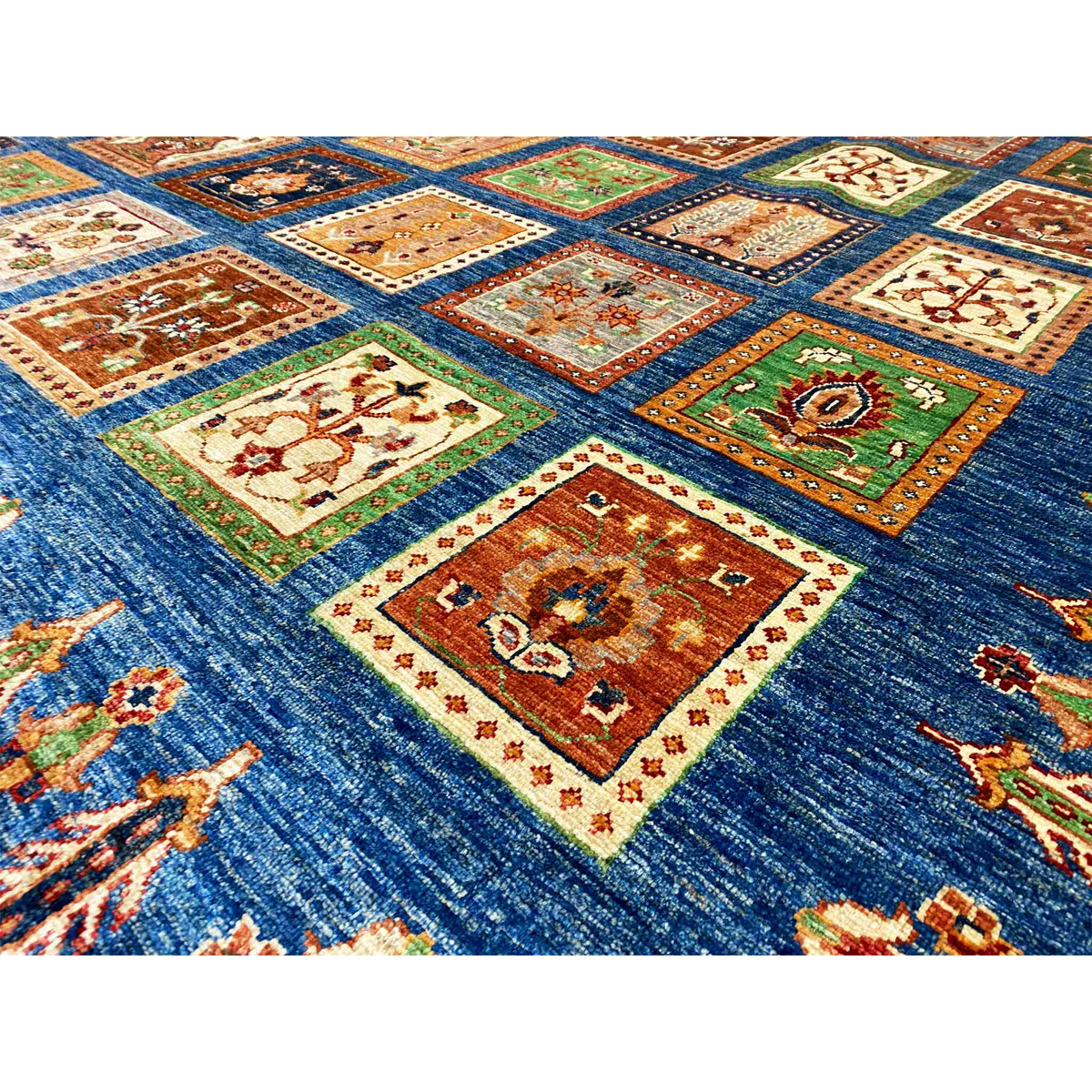 Blue rug with Khorjin squares in orange, green, and cream, close-up
