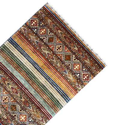 Corner view of a Khorjin rug: stripes, diamonds, and colorful fringes