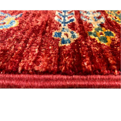 Close-up: red carpet pile with colorful patterns, visible fringes