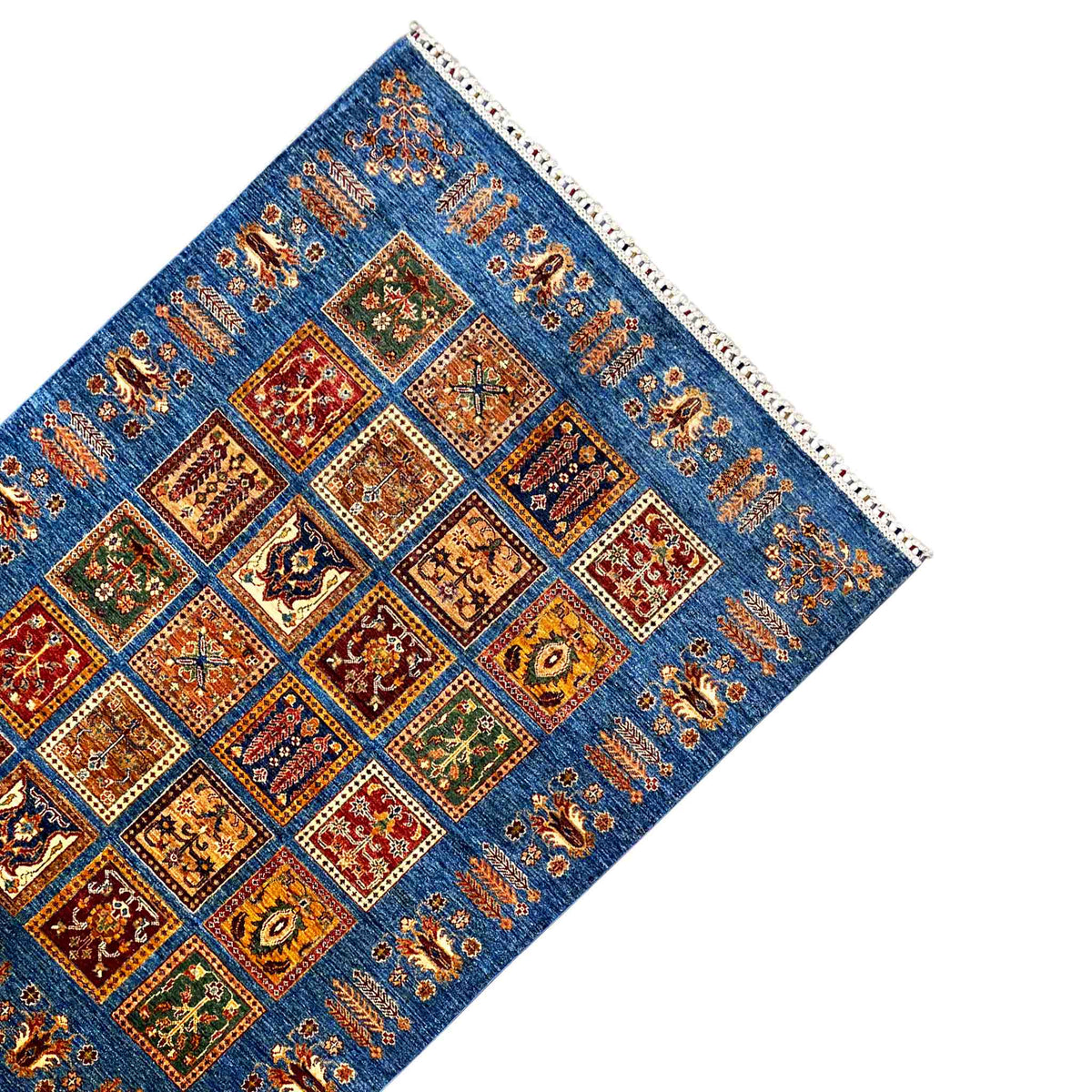 Khorjin rug at an angle: blue field with ornamental squares, border ornaments, and fringes