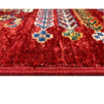 Red floral rug with a woven pattern and fringed border