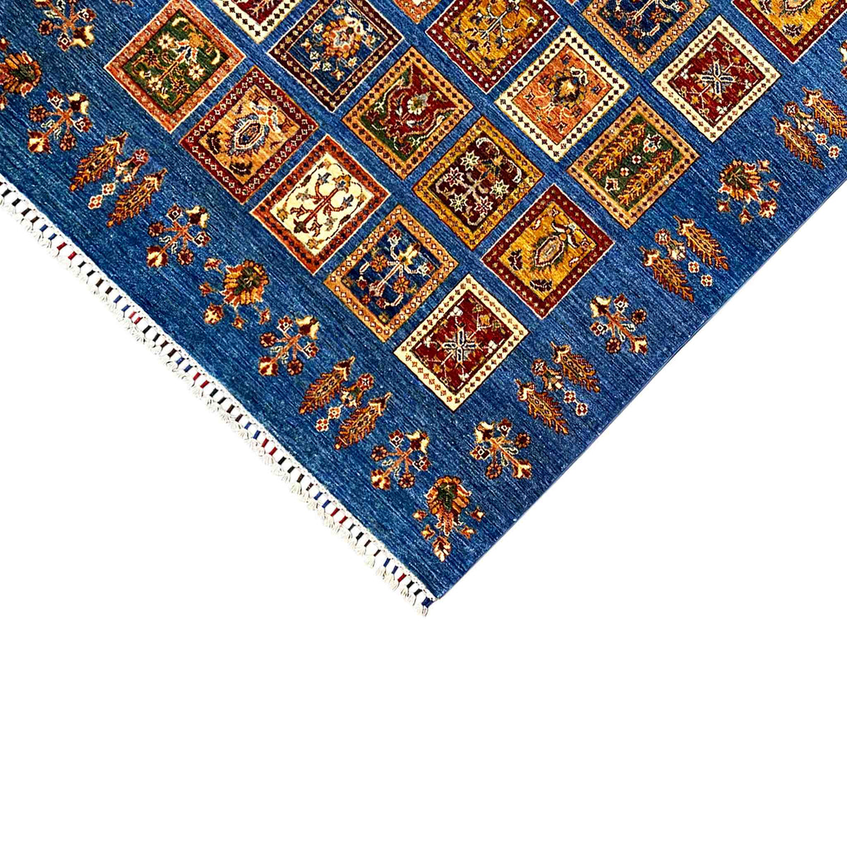 Carpet corner view with an azure-blue background, colorful squares, white fringe trim, and border