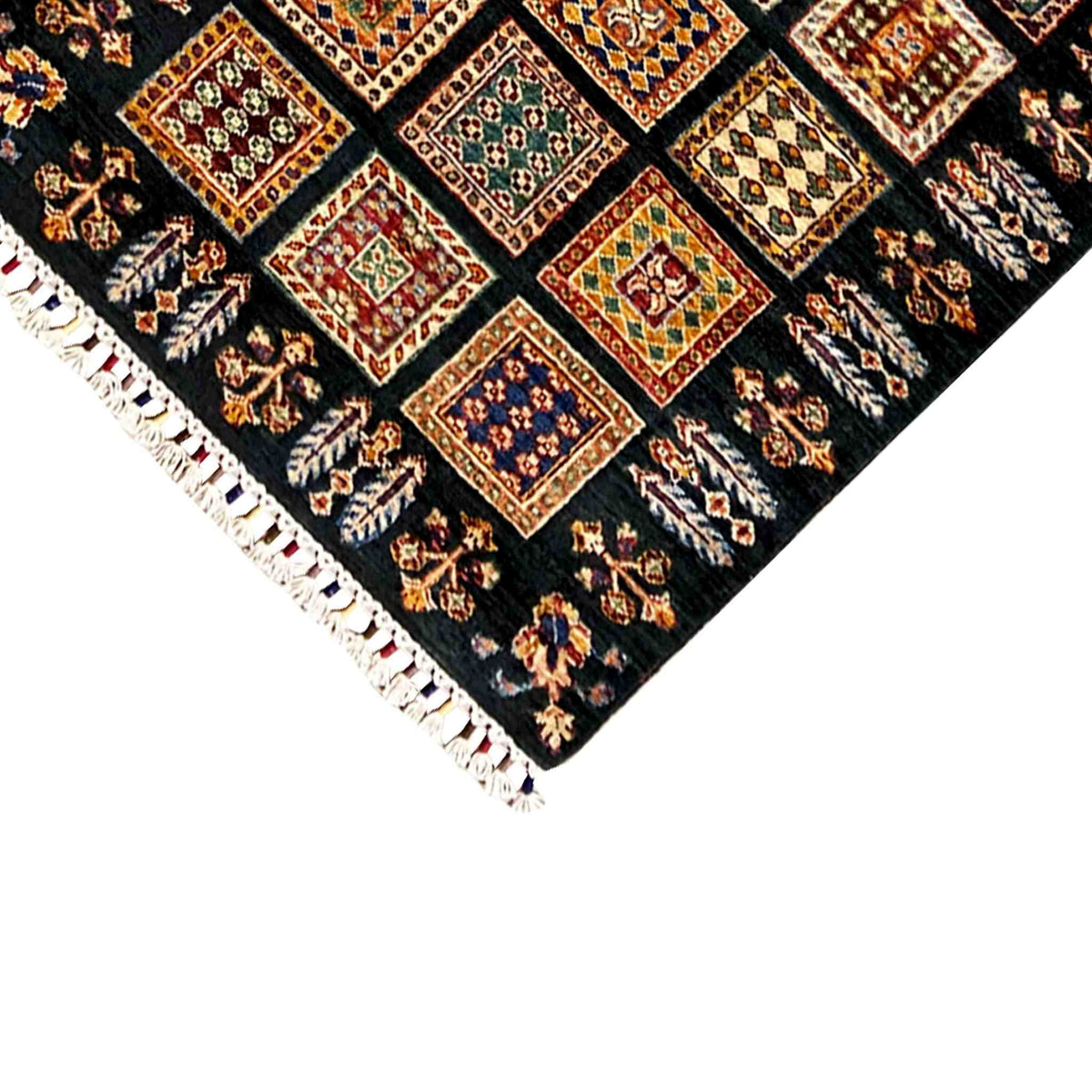 Corner of the runner rug with fringe, dark background, and multicolored squares