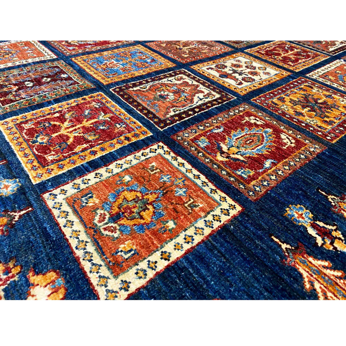 Detailed view of the wool rug: dark blue pattern with red, orange, and beige tiles