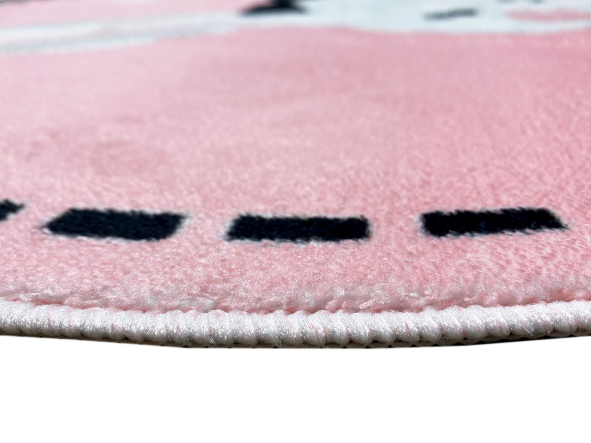 Nahaufnahme vom runden Kinderteppich: rosa Flor, schwarze Markierungen, helle Kettelnaht