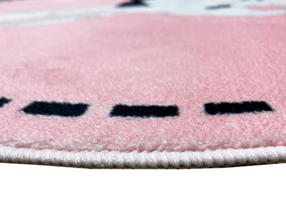 Nahaufnahme vom runden Kinderteppich: rosa Flor, schwarze Markierungen, helle Kettelnaht