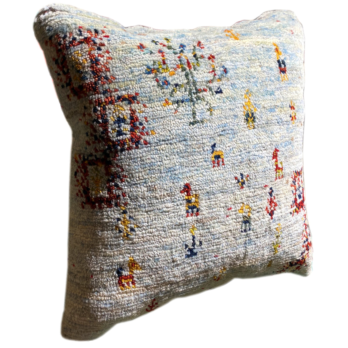 Light blue decorative cushion, side view, with colorful embroidered figures