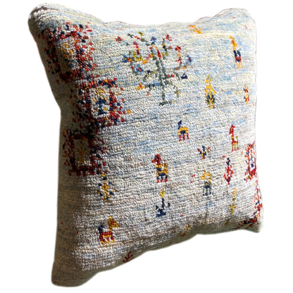 Light blue decorative cushion, side view, with colorful embroidered figures