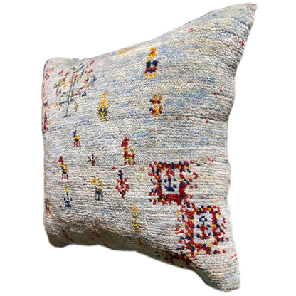 Light blue decorative cushion with colorful embroidered figures and a sideways gaze