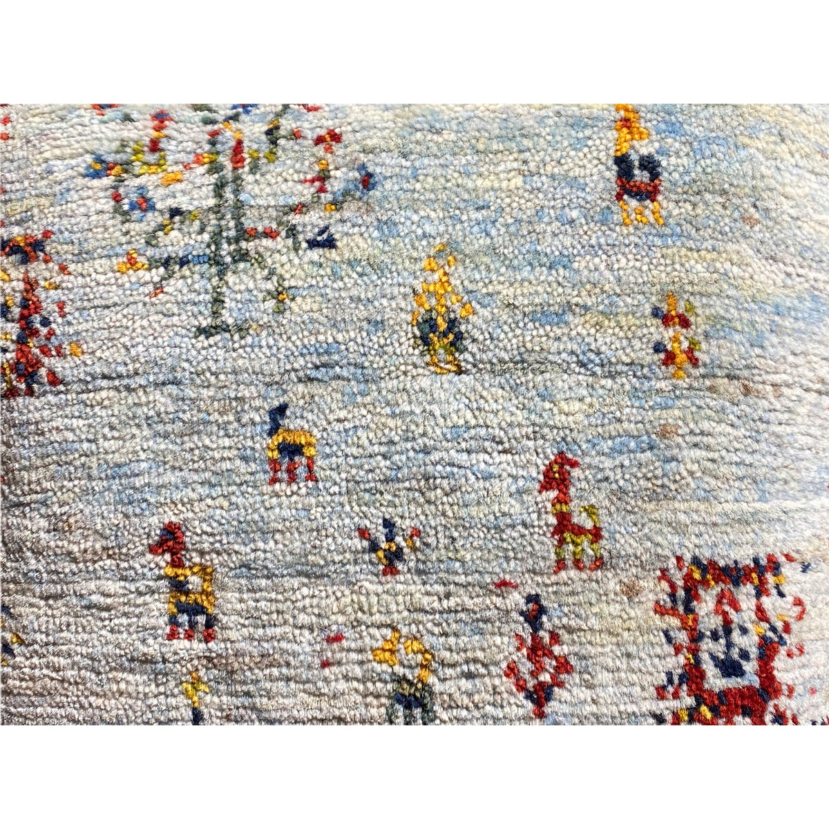 Close-up: light-colored cushion with a coarse weave and colorful embroidered figures
