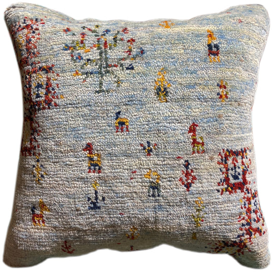 Light blue decorative cushion with colorful embroidered figures in a patchwork look