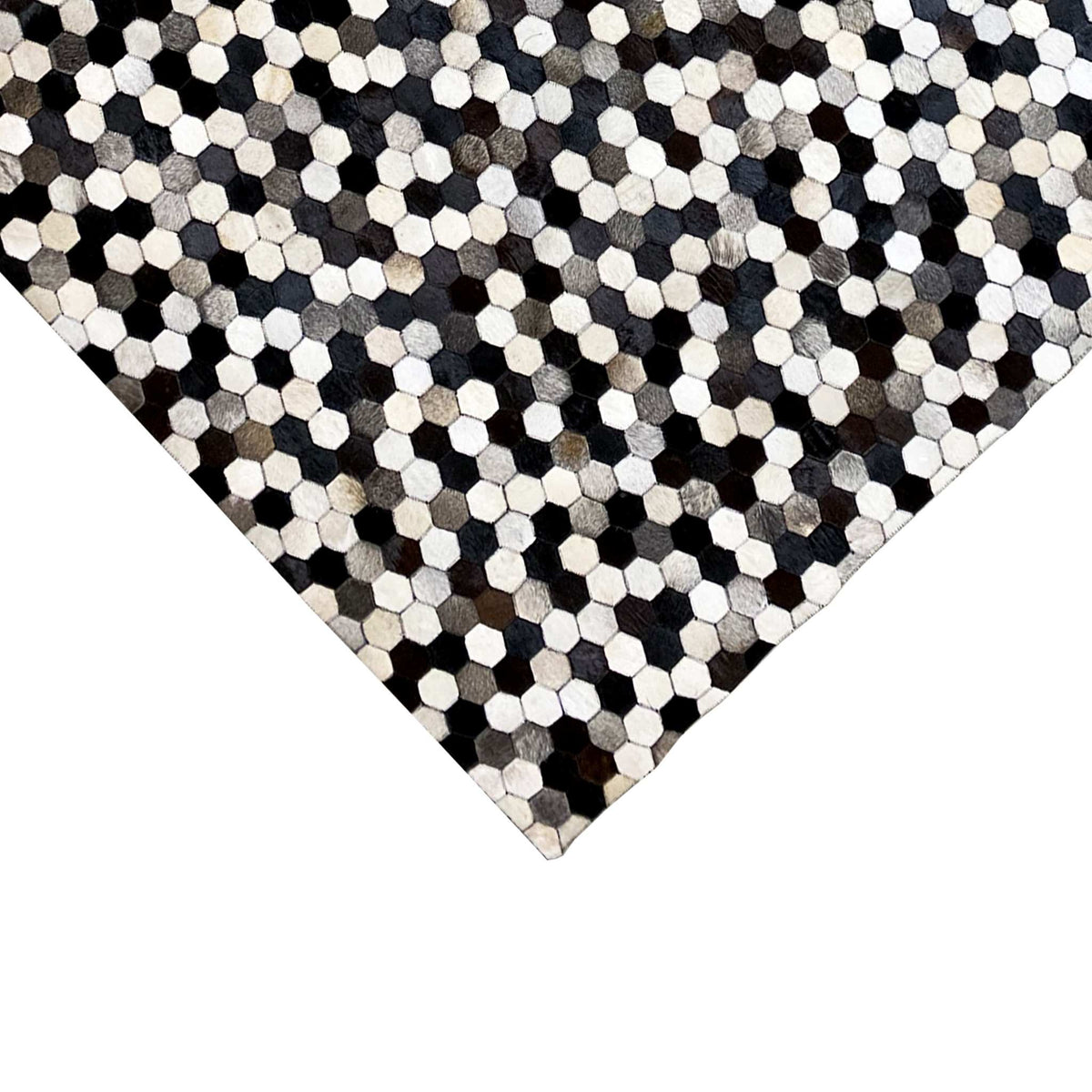 Calfskin rug in a dark and light hexagon pattern, with a rectangular corner and edges visible