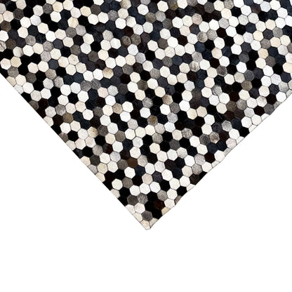 Calfskin rug in a dark and light hexagon pattern, with a rectangular corner and edges visible