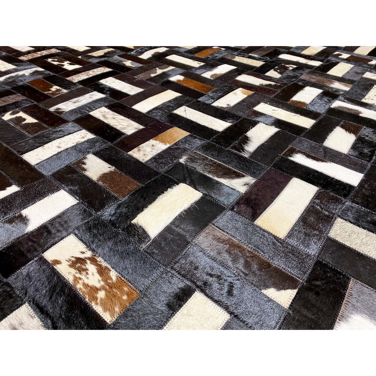Close-up of a calfskin rug: dark blocks, light gray and white stripes, brown spots
