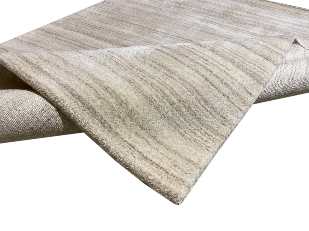 Folded rug with a beige base and fine, wavy stripes