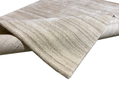 Folded rug with a beige base and fine, wavy stripes