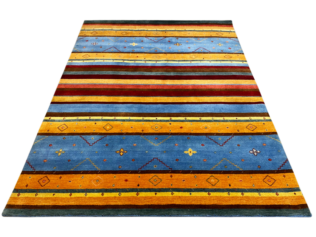 Loom Luri Teppich von oben: gleichmäßige Streifen in Blau, Orange, Rot und Grün.
