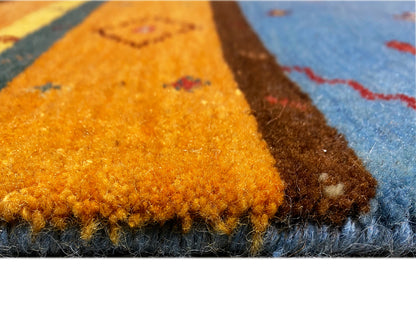 Loom Luri Teppich Nahaufnahme: Flor wirkt flauschig, blaues und orangefarbenes Muster im Wechsel.