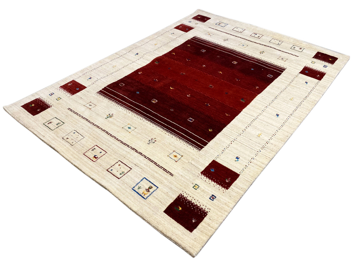 Loom Luri Teppich mit cremefarbenem Hintergrund, rotem Zentrum und farbigen Eckmotiven