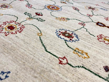 Teppichdetail in Creme mit bunten Ornamenten und feinen Linien, nah aufgenommen.