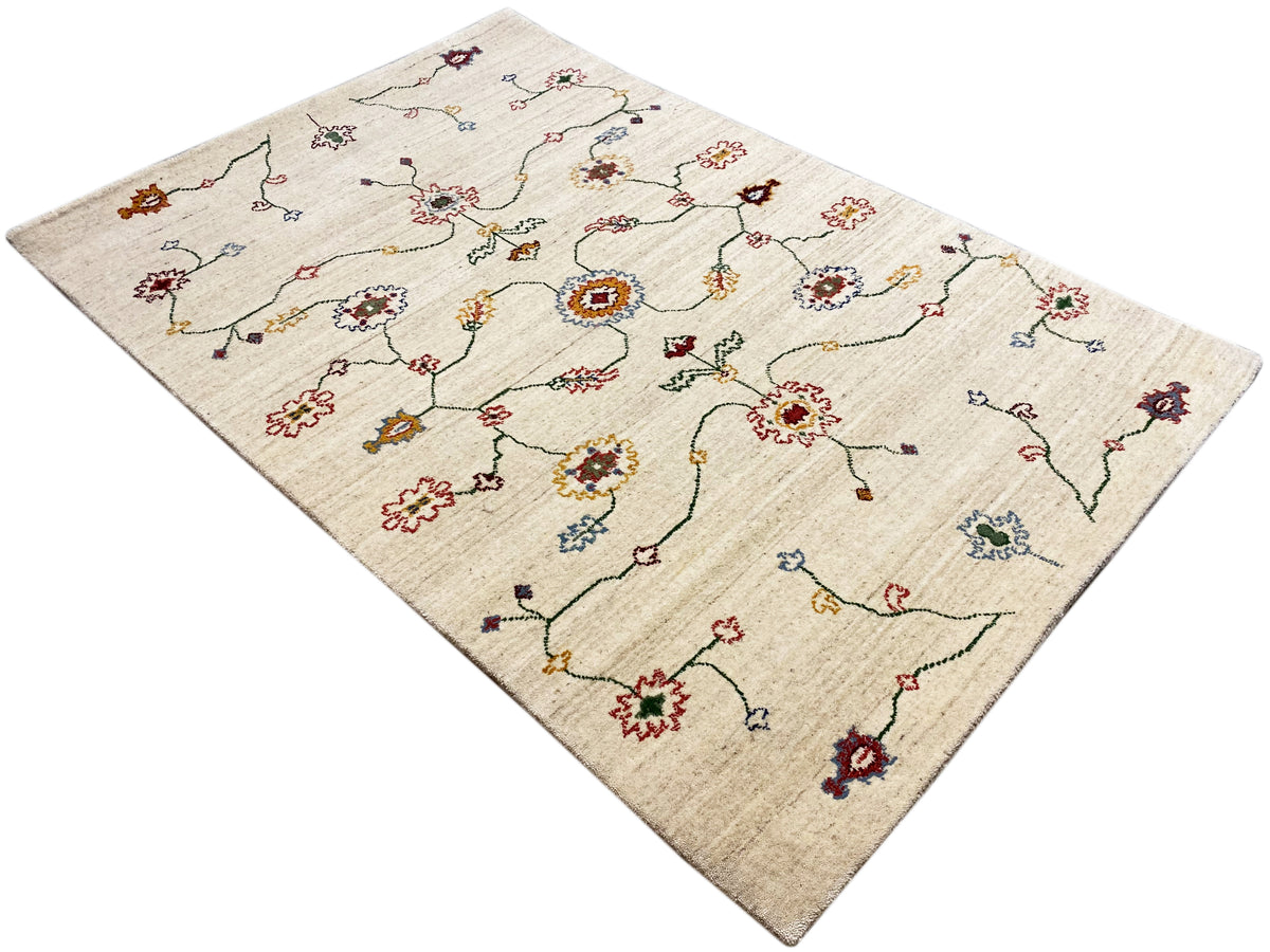 Teppich 119×180 cm in Creme mit buntem Ornamentmuster, schräg ausgerichtet.