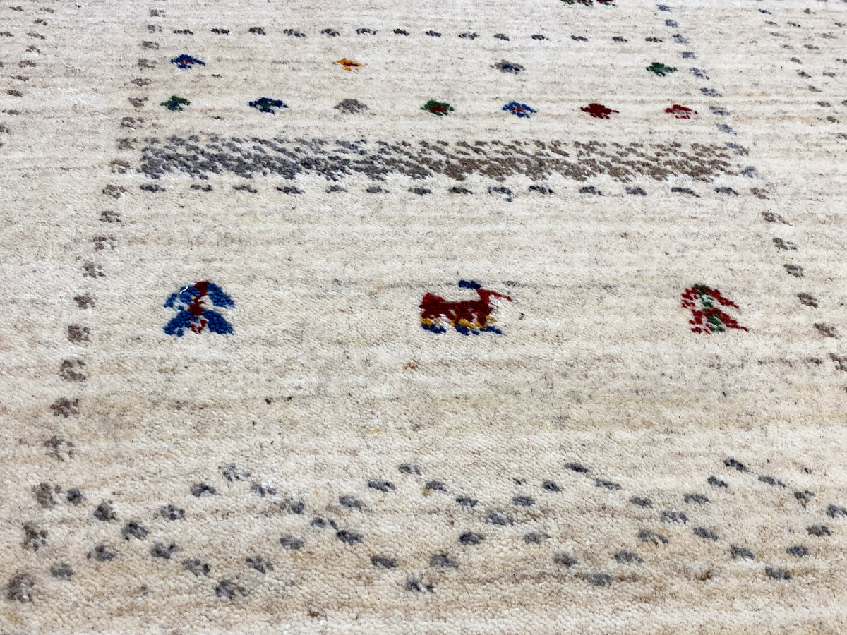 Nahaufnahme Muster: helle Grundfarbe mit bunten Figuren und feinen Punktreihen entlang