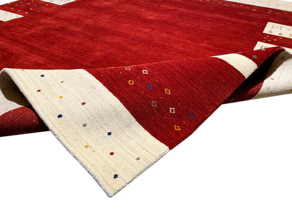 Roter Teppich mit beigem Rand und kleinen bunten Punkten, seitlich aufgeschlagenes Eck