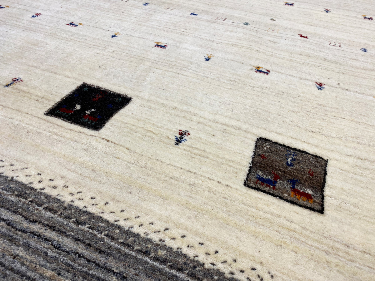 Teppichdetail: rechteckige schwarze Felder und farbige Punkte auf beigem Grund
