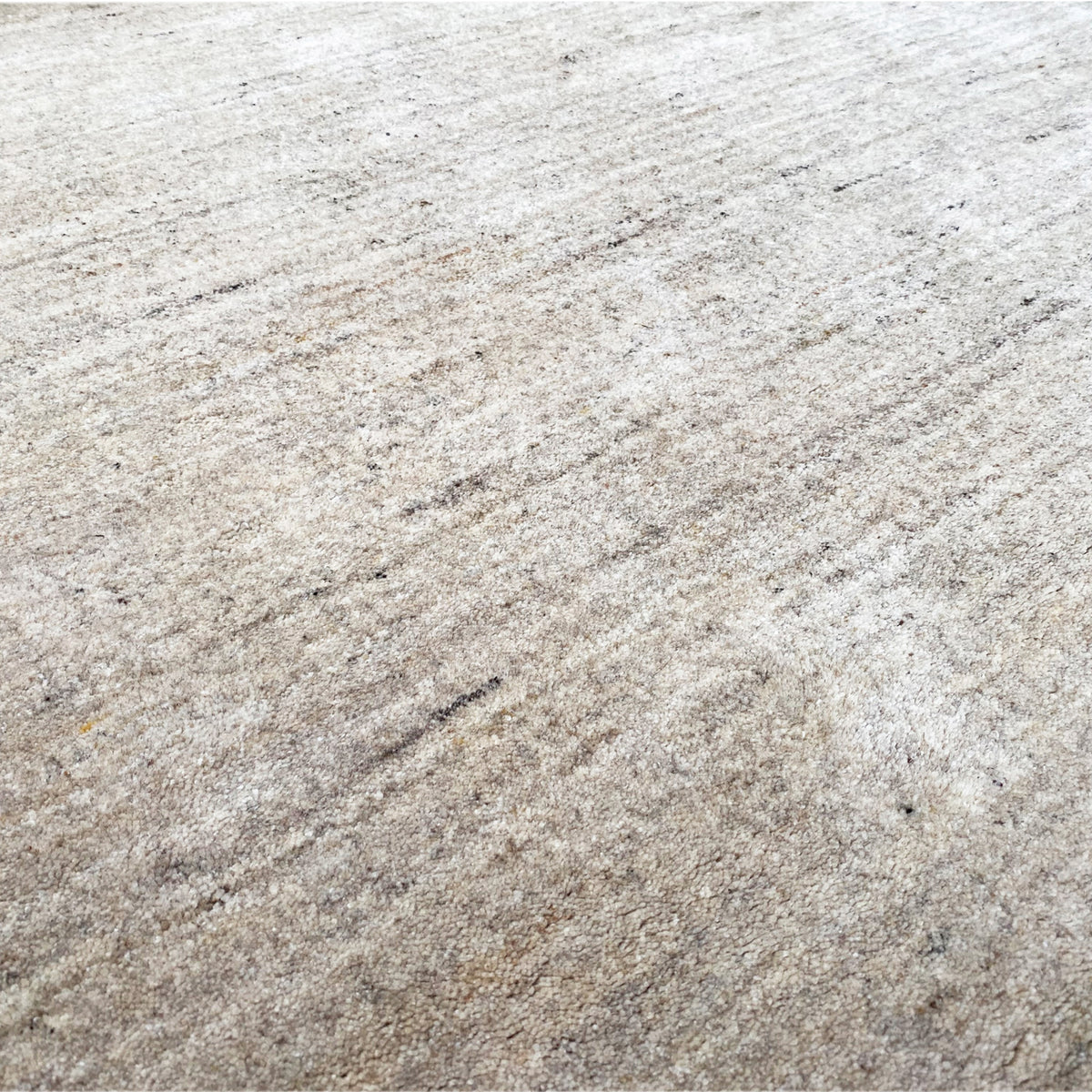 Beige rug with mottled short pile and fine, irregular lines