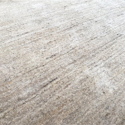 Beige rug with mottled short pile and fine, irregular lines
