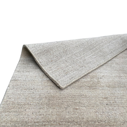 Close-up: beige carpet with a turned-up edge and subtly mottled surface