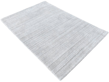 Loom Luri Teppich, hellgrau, gefaltet, Oberfläche mit feiner, gleichmäßiger Linienprägung.