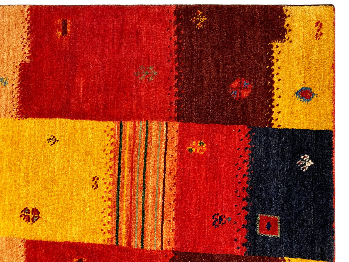 Loom Luri Teppich Detail: rote und gelbe Flächen mit dunklen Mustern und klaren Kanten