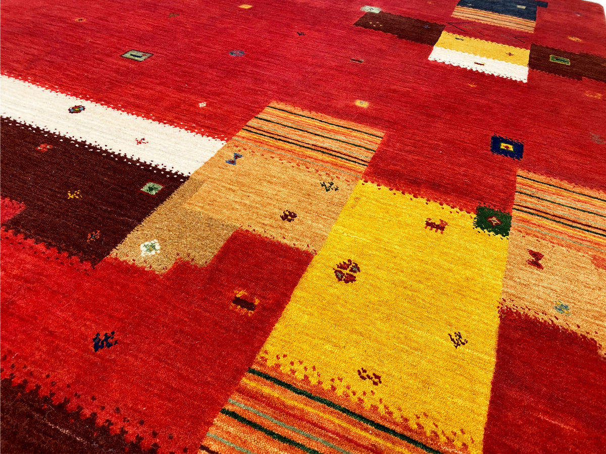Loom Luri Teppich Detailansicht: rotes Patchwork mit gelben, weißen und grün akzentuierten Linien