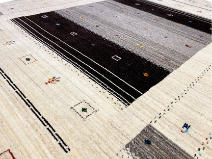 Detailansicht Loom Luri-Teppich: beiger Stoff mit schwarzen Linien, Punkten und farbigen Mini-Motiven