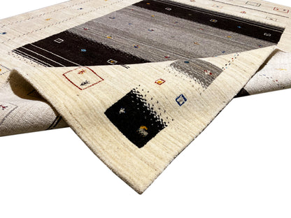 Loom Luri-Teppich 240x176 cm Nahansicht: aufgerollte Ecke mit beige Flor und dunklem Innenmuster