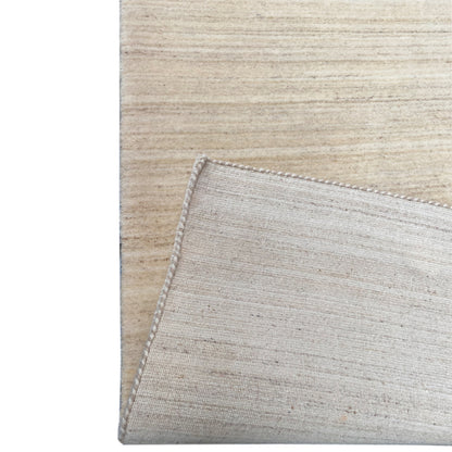 Natural gabbeh rug, detail of overlock stitching along the rug edge, light beige