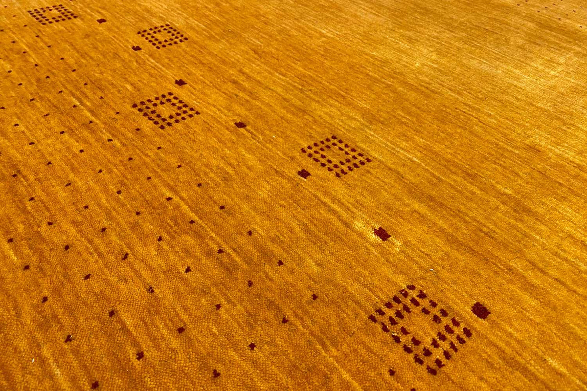 Gabbeh rug detail view: honey-brown surface with dark square motifs