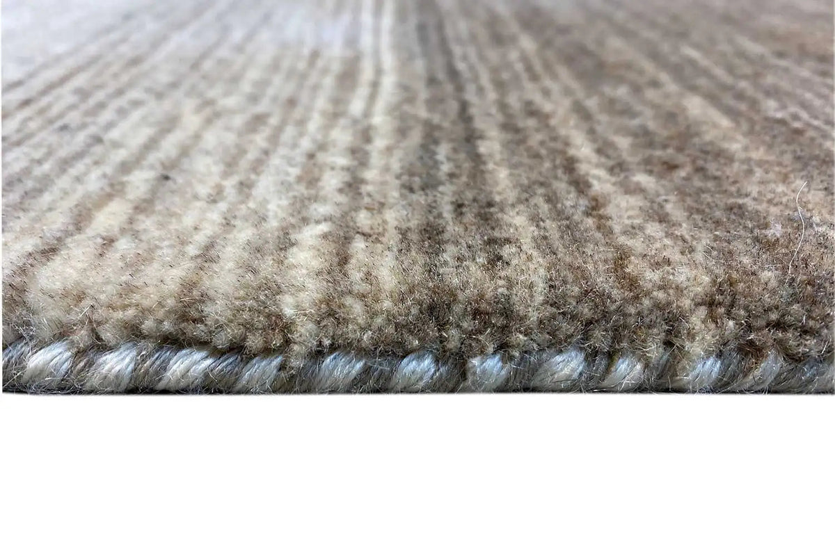 Carpet edge with short mottled pile in gray and beige, visible pile finish.