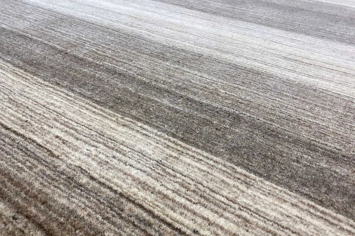 Carpet surface with fine horizontal lines and dense, short pile in gray and beige.