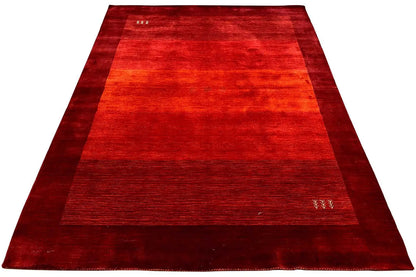 Overview of a red Gabbeh rug with narrow borders and an even pattern.