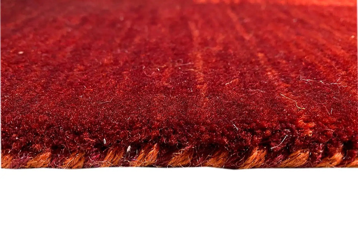 Red Gabbeh rug with a visible pile and a finished edge with fringes.