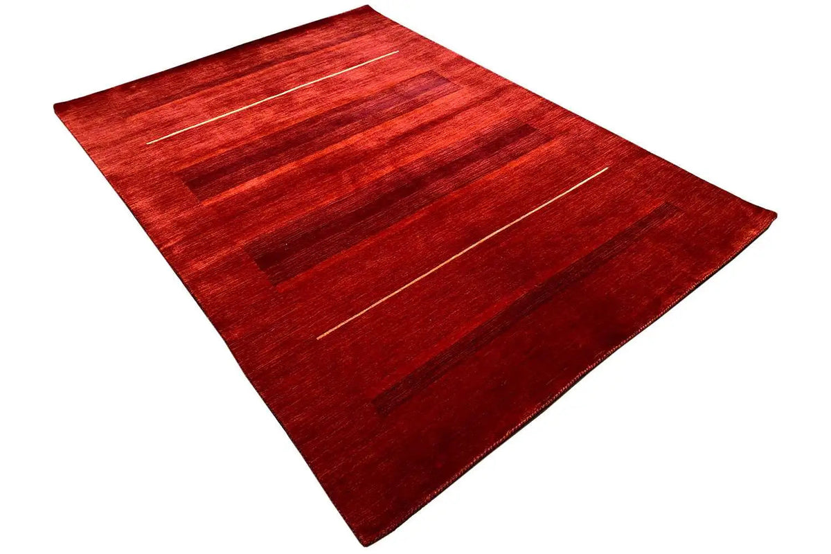 Gabbeh rug with diagonal striped lines in shades of red, viewed from above at an angle