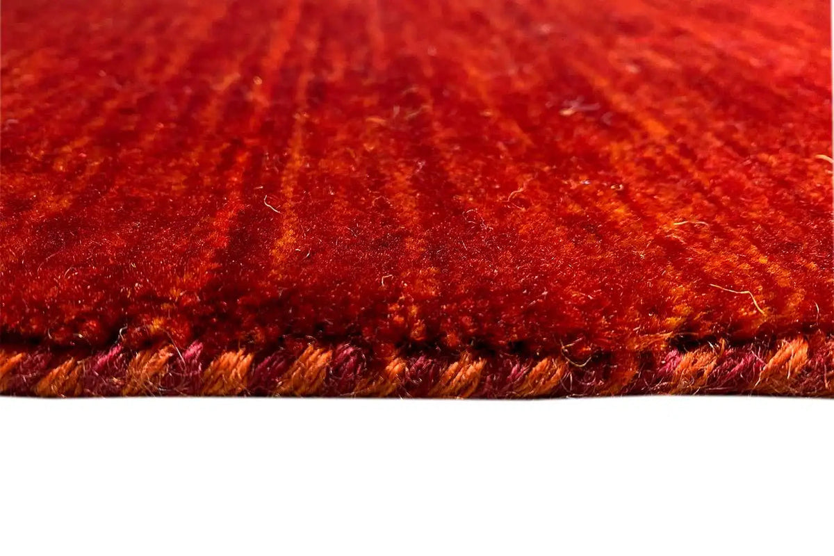 Gabbeh rug with dense pile, red-orange color gradient, and fringed edges, detail