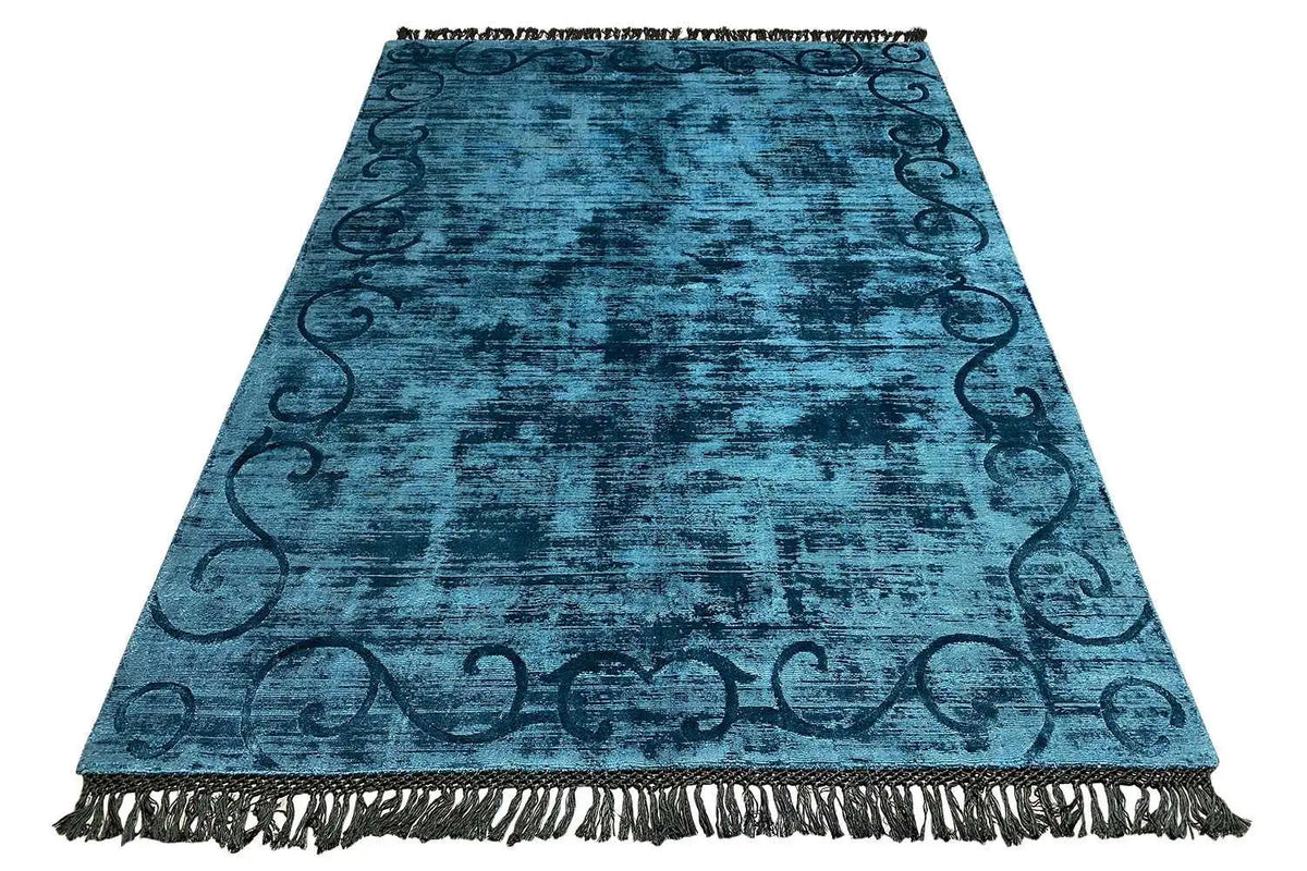 Blue Gabbeh rug in triangular view, with fringes all around and an ornamental border