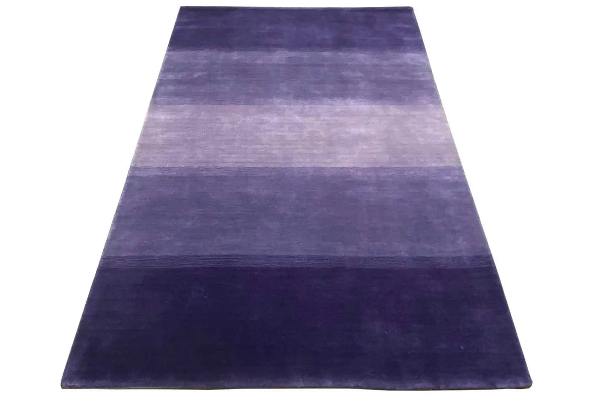 Gabbeh rug in a triangular view: stripes in violet, blue, and light purple tones.