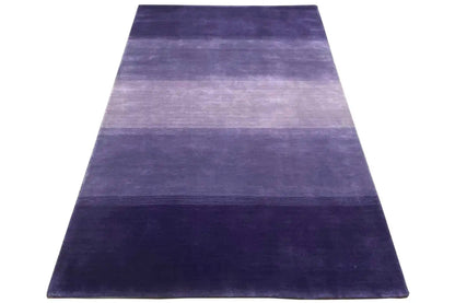 Gabbeh rug in a triangular view: stripes in violet, blue, and light purple tones.